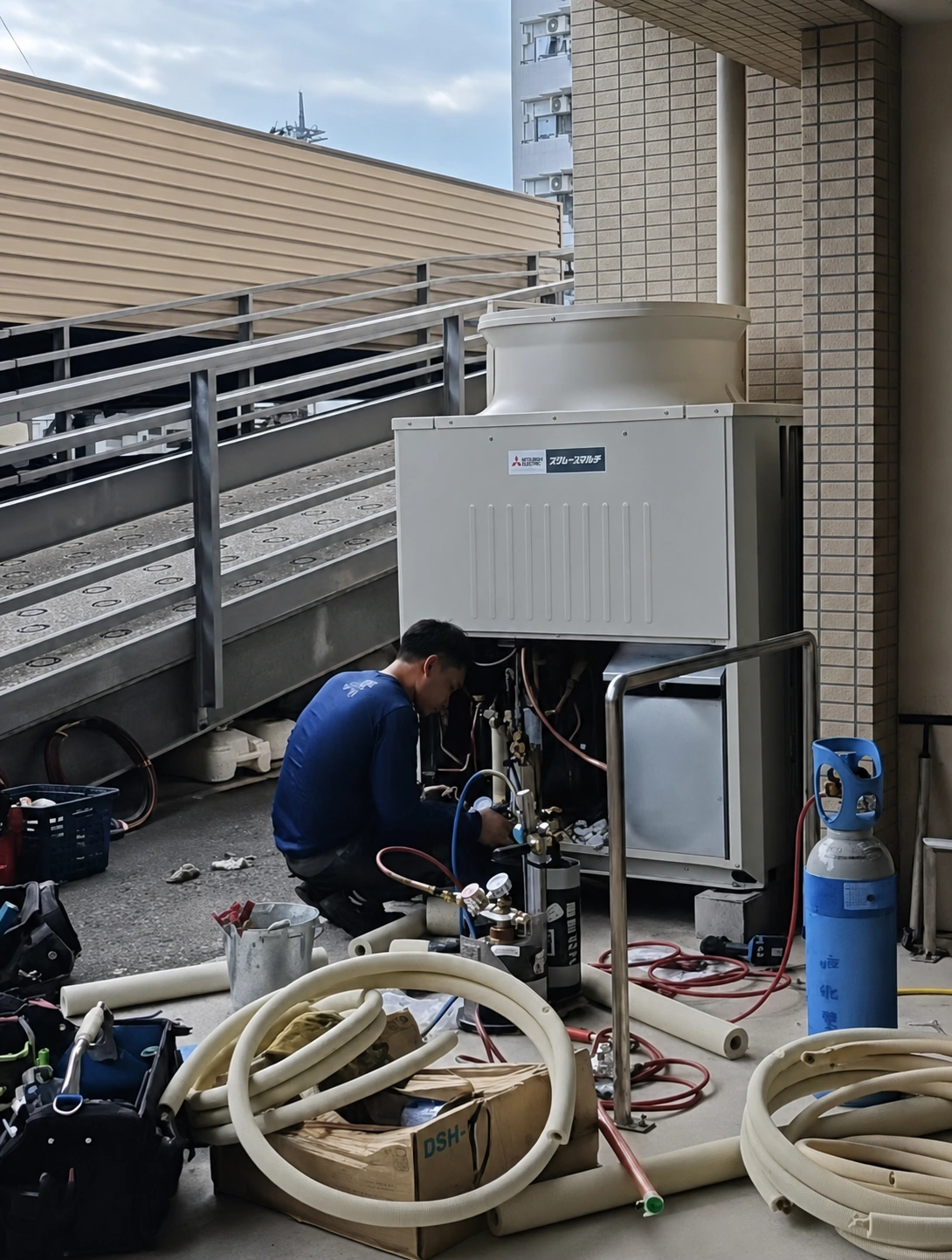 建物設備スペースで業務用空調室外機を整備する技術者